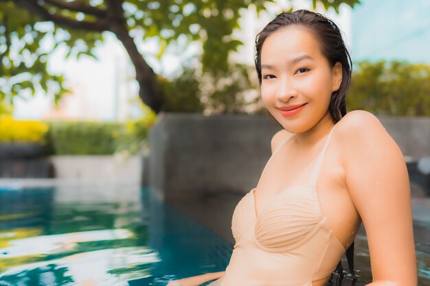 肖像画の美しい若いアジア女性は屋外スイミングプールの周りの幸せな笑顔レジャーをリラックスします。