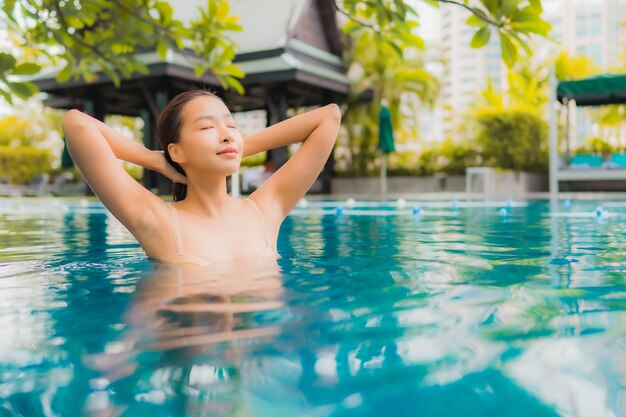 肖像画の美しい若いアジア女性は屋外スイミングプールの周りの幸せな笑顔レジャーをリラックスします。