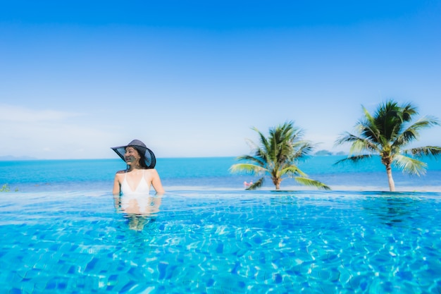Бесплатное фото Портрет красивая молодая азиатская женщина расслабиться в роскошном открытом бассейне в отеле курорта почти пляж море океан