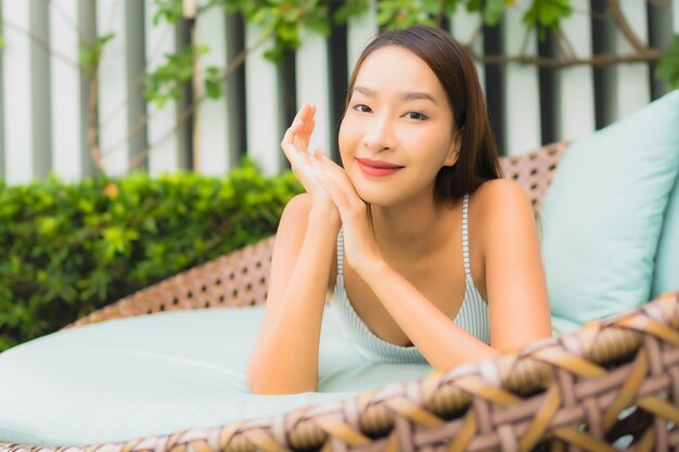 Женщина портрета красивая молодая азиатская ослабляет отдых вокруг открытого бассейна в курорте гостиницы на каникулы перемещения