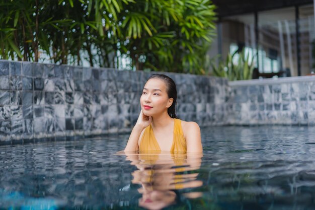 Женщина портрета красивая молодая азиатская ослабляет отдых вокруг бассейна