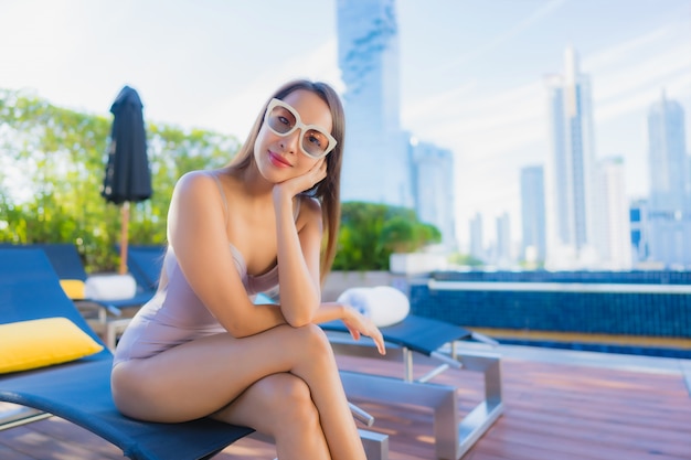 Женщина портрета красивая молодая азиатская ослабляет отдых наслаждается вокруг открытого бассейна