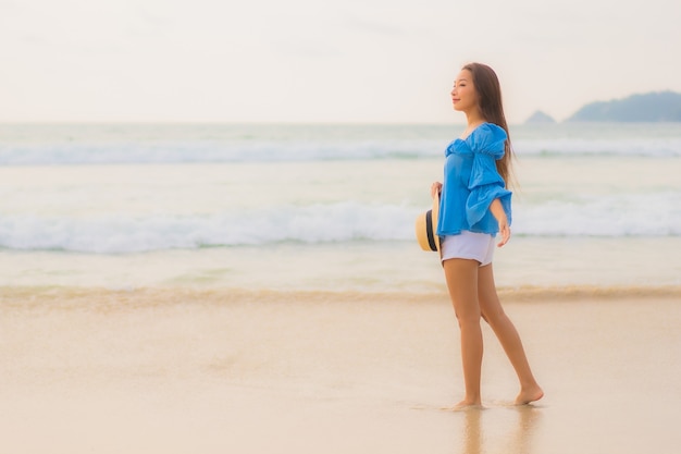 세로 아름 다운 젊은 아시아 여자는 일몰 시간에 해변 바다 바다 주위 여가 미소를 긴장