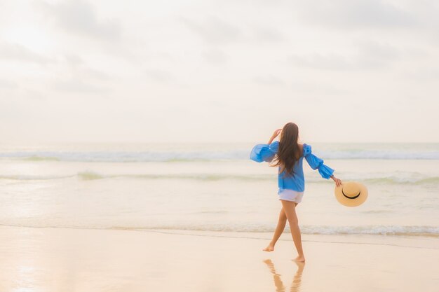 肖像画美しい若いアジアの女性は日没時にビーチの海の海の周りのレジャー笑顔をリラックス