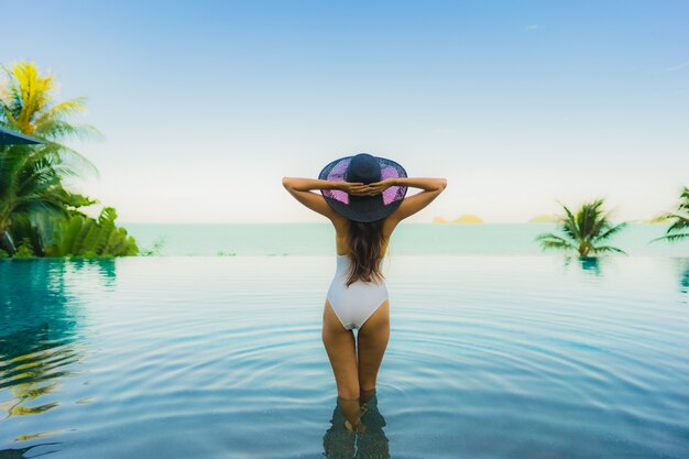 Портрет красивая молодая азиатская женщина расслабиться в роскошном открытом бассейне в отеле курорта почти пляж море океан