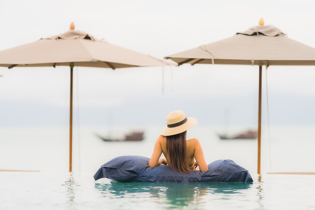 Портрет красивая молодая азиатская женщина расслабиться в роскошном открытом бассейне в отеле курорта почти пляж море океан