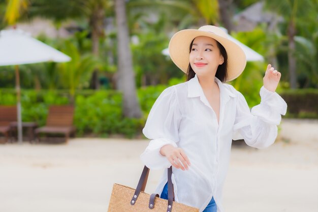 肖像画美しい若いアジアの女性は、休日の休暇旅行旅行でビーチの海の海の周りの笑顔をリラックス