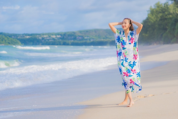 Женщина портрета красивая молодая азиатская ослабляет улыбку вокруг океана моря пляжа в отпуске