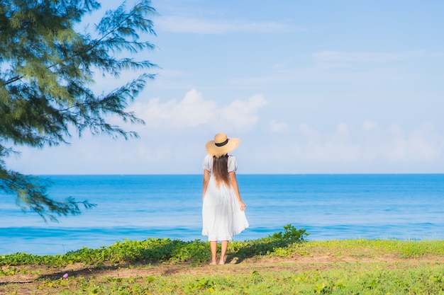 肖像画美しい若いアジアの女性は旅行休暇のための青い空と白い雲とビーチの海の海の周りの笑顔をリラックス