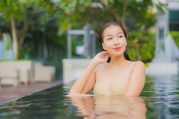 Женщина портрета красивая молодая азиатская ослабляет улыбку вокруг открытого бассейна в курорте гостиницы в путешествии каникул