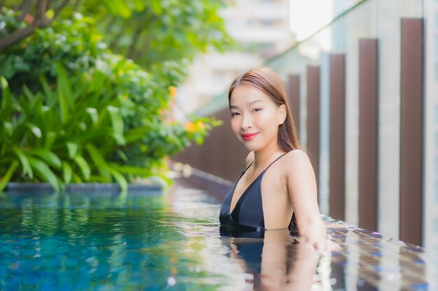 Portrait beautiful young asian woman relax smile around outdoor swimming pool in hotel resort