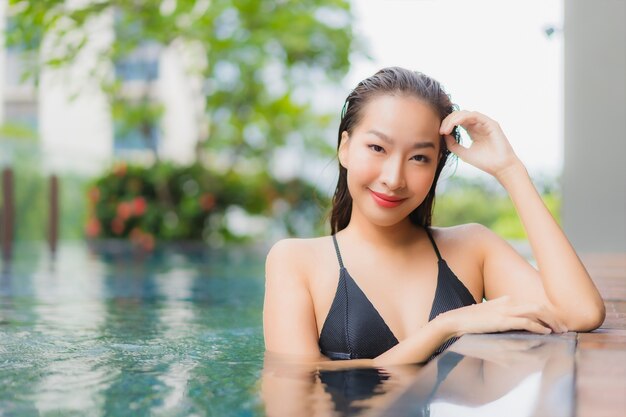 초상화 아름 다운 젊은 아시아 여자는 호텔 리조트에서 야외 수영장 주위에 미소를 긴장