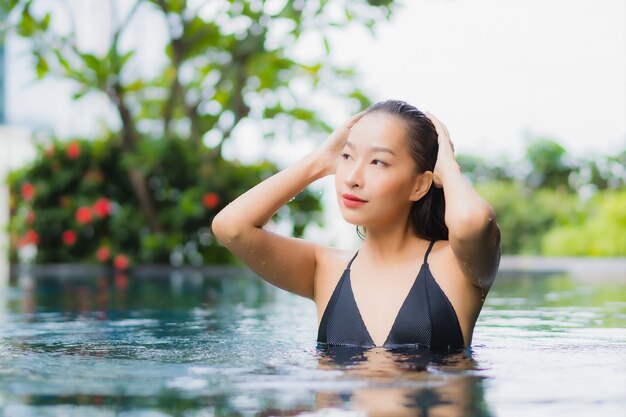 Portrait beautiful young asian woman relax smile around outdoor swimming pool in hotel resort