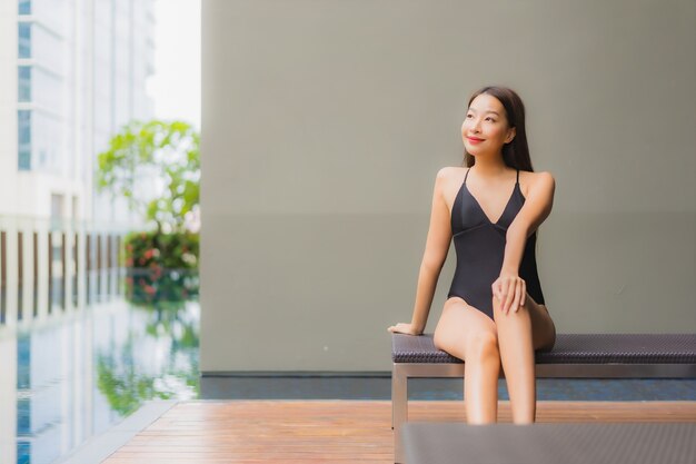 Portrait beautiful young asian woman relax smile around outdoor swimming pool in hotel resort