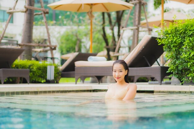 Portrait beautiful young asian woman relax smile around outdoor swimming pool in hotel resort