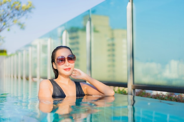 Foto gratuita la bella giovane donna asiatica del ritratto si rilassa il sorriso intorno alla piscina all'aperto nella località di soggiorno dell'hotel