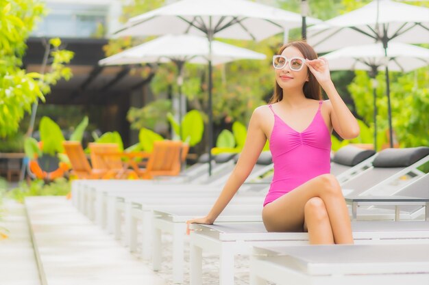 초상화 아름 다운 젊은 아시아 여자는 호텔 리조트에서 야외 수영장 주위에 미소를 긴장