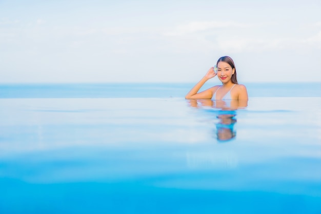 무료 사진 초상화 아름 다운 젊은 아시아 여자는 호텔 리조트에서 야외 수영장 주위에 미소를 긴장