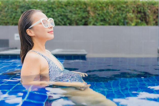 세로 아름 다운 젊은 아시아 여자 야외 수영장 주위 미소를 긴장