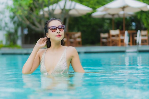 Женщина портрета красивая молодая азиатская ослабляет улыбку вокруг открытого бассейна