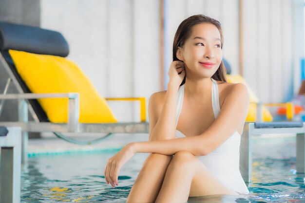 세로 아름 다운 젊은 아시아 여자는 traval 휴가에 호텔 리조트에서 수영장 주위에 미소를 긴장