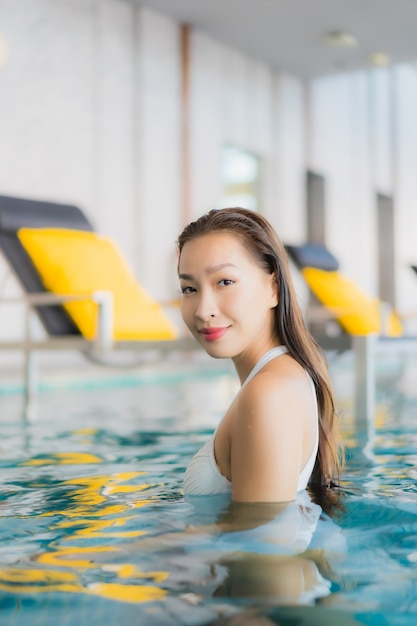 La bella giovane donna asiatica del ritratto si rilassa il sorriso intorno alla piscina nella località di soggiorno dell'hotel sulla vacanza di traval