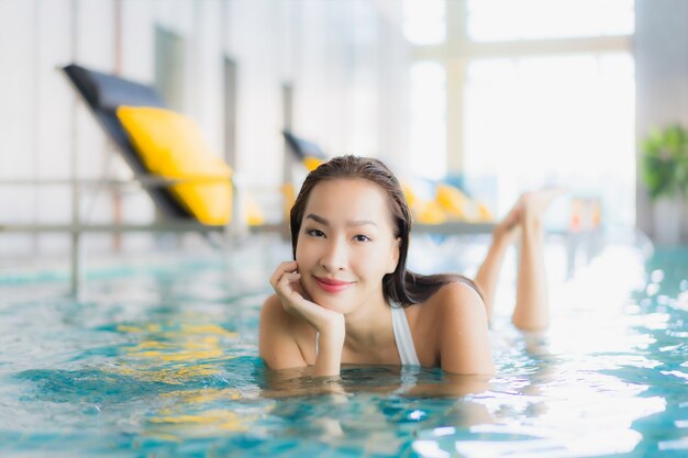 세로 아름 다운 젊은 아시아 여자는 traval 휴가에 호텔 리조트에서 수영장 주위에 미소를 긴장