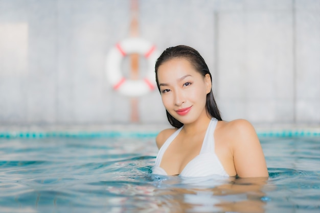 Женщина портрета красивая молодая азиатская ослабляет улыбку вокруг бассейна в курорте гостиницы на каникулах traval