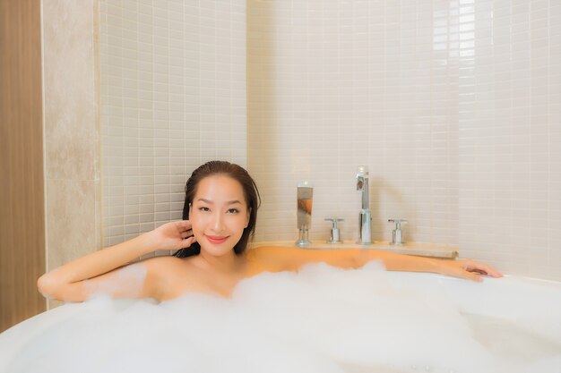 초상화 아름 다운 젊은 아시아 여자 욕실 인테리어에 욕조에 미소를 긴장