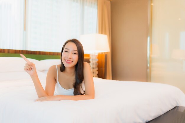 Portrait beautiful young asian woman relax smile on bed in bedroom interior