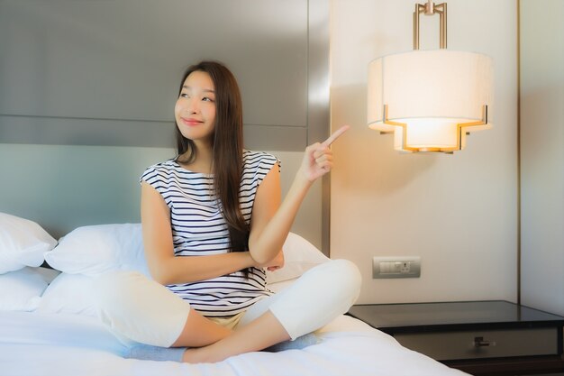 Portrait beautiful young asian woman relax smile on bed in bedroom interior