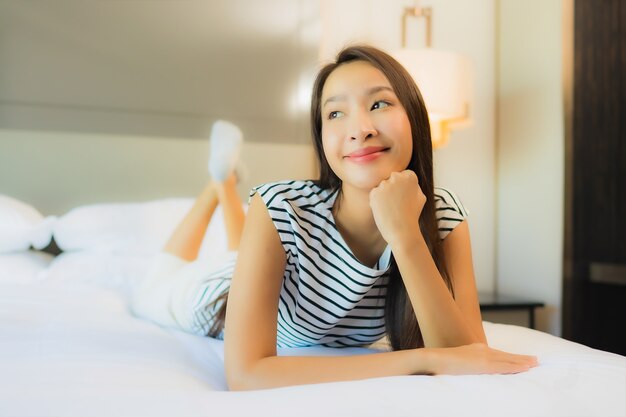 Portrait beautiful young asian woman relax smile on bed in bedroom interior