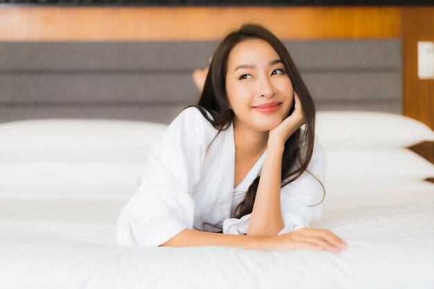 Portrait beautiful young asian woman relax smile on bed in bedroom interior