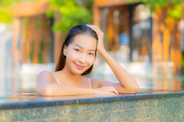 Женщина портрета красивая молодая азиатская ослабляет улыбку наслаждается отдыхом вокруг бассейна на курорте гостиницы