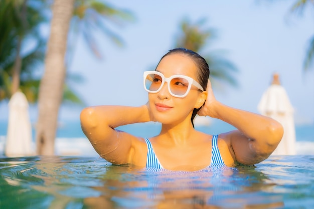 초상화 아름 다운 젊은 아시아 여자 휴식 미소 휴가에 거의 바다 해변 바다 전망 수영장 주변 레저를 즐길 수