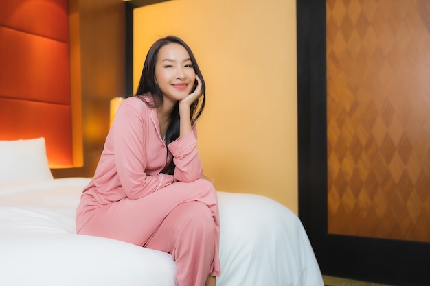 Free photo portrait beautiful young asian woman relax smile happy on bed in bedroom interior