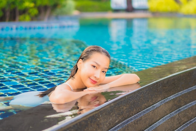 肖像画美しい若いアジアの女性は、海の近くの屋外プールの周りの笑顔のレジャーをリラックス