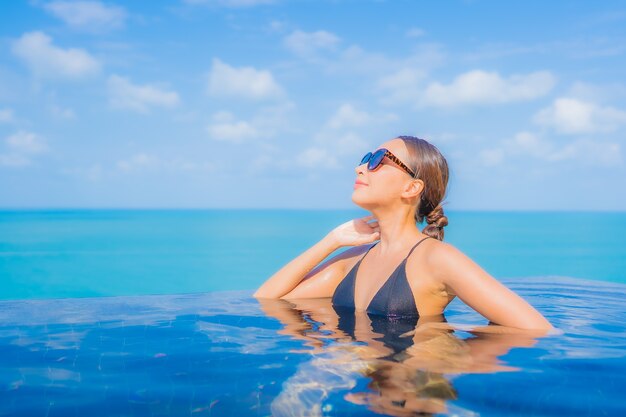 Portrait beautiful young asian woman relax smile leisure around outdoor swimming pool in resort hotel with sea ocean view