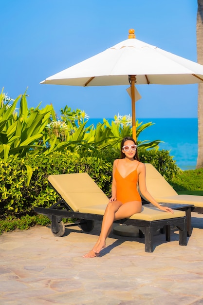 Portrait beautiful young asian woman relax smile leisure around outdoor swimming pool with sea ocean view