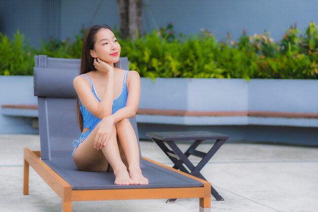 Женщина портрета красивая молодая азиатская ослабляет отдых улыбки вокруг открытого бассейна