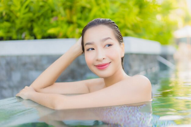 肖像画美しい若いアジアの女性は、屋外スイミングプールの周りの笑顔のレジャーをリラックス