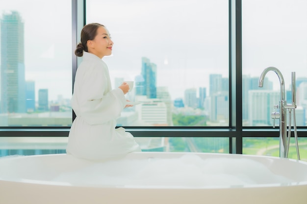 Foto gratuita la bella giovane donna asiatica del ritratto si rilassa il tempo libero di sorriso nella vasca da bagno nell'interno del bagno