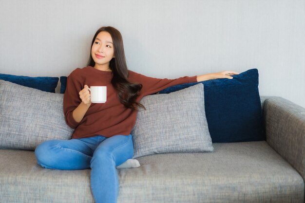 Portrait beautiful young asian woman relax smile on sofa in living room interior