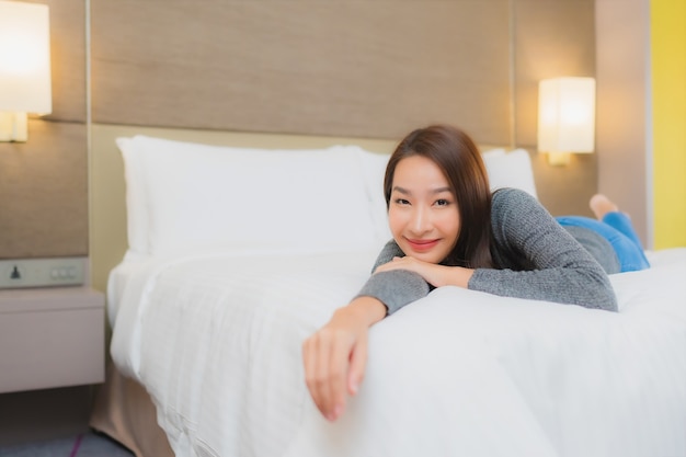 아름 다운 젊은 아시아 여자의 초상화는 침실에서 침대에 이완
