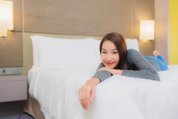 Портрет красивой молодой азиатской женщины расслабляется на кровати в спальне