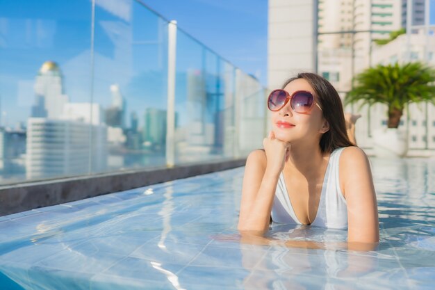 Женщина портрета красивая молодая азиатская ослабляет отдых вокруг бассейна