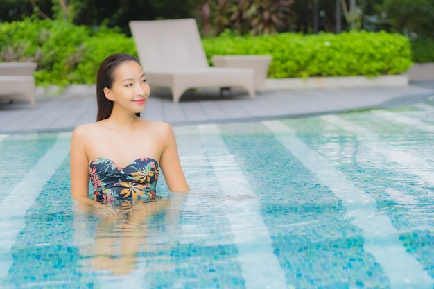 Portrait of beautiful young asian woman relaxes on the swimming pool in hotel resort