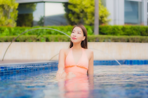 Portrait of beautiful young asian woman relaxes on the swimming pool in hotel resort