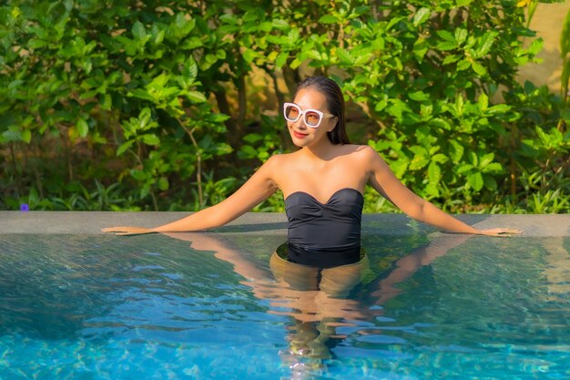 Портрет красивой молодой азиатской женщины расслабляется в бассейне