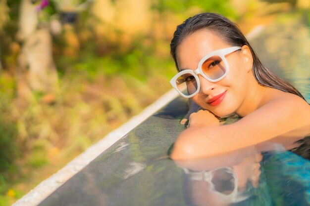 Портрет красивой молодой азиатской женщины расслабляется в бассейне